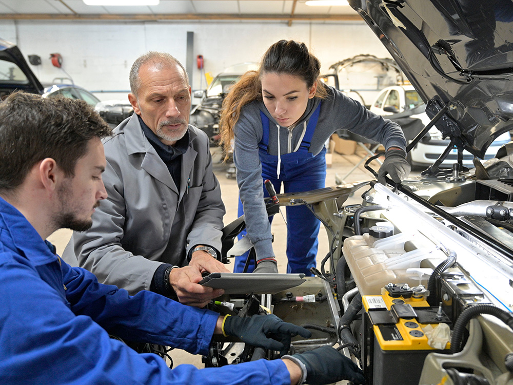 Automotive instructor showing high school students a car engine