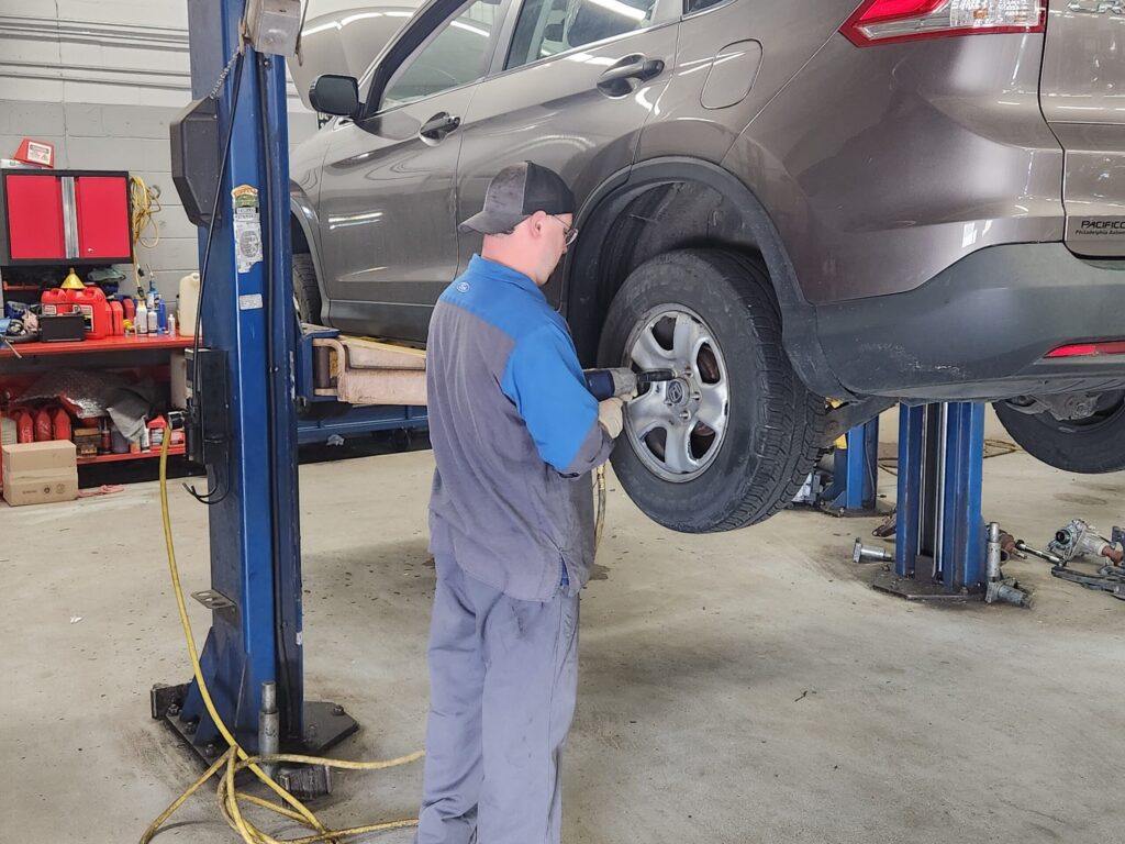 Technician working on vehicle's wheel on a lift.