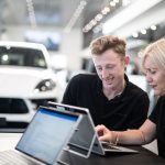 Trainer using a laptop to teach an automotive student